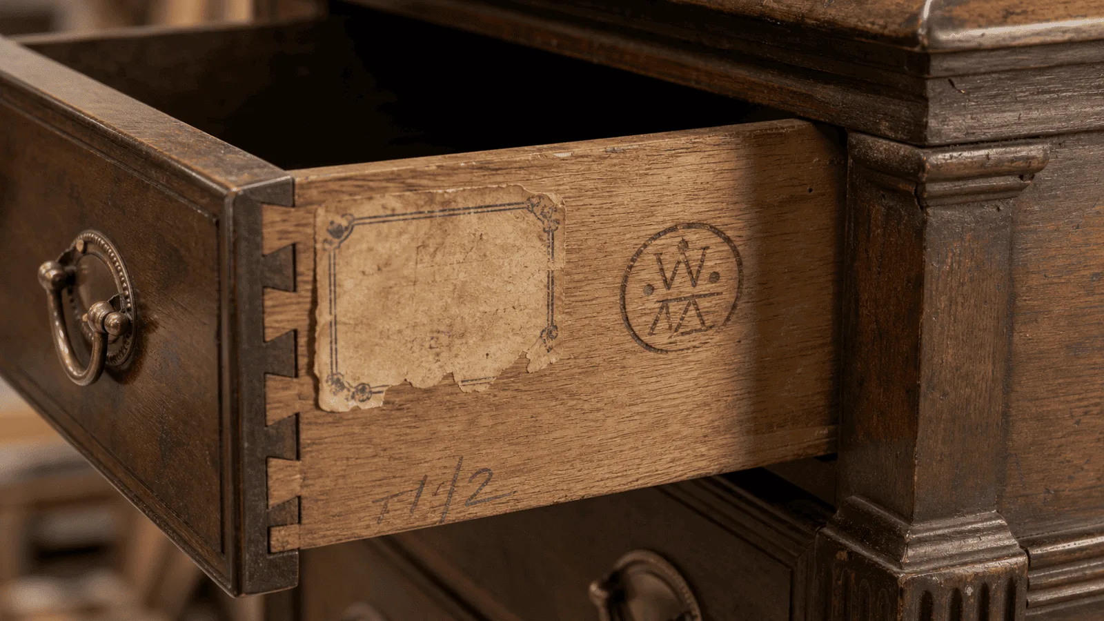 Furniture maker marks on the underside of an antique drawer with labels, stamps, and dovetail joints