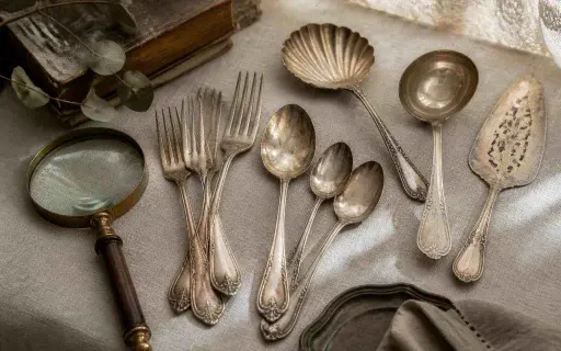 Antique silverware arranged on a table for appraisal review