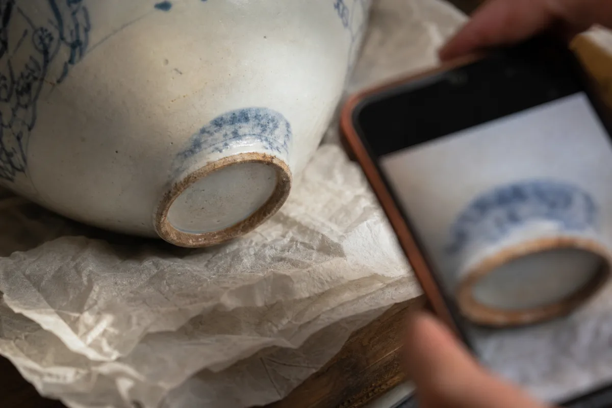 Documenting an incomplete backstamp Close illustration of a worn blue impression on a porcelain base being photographed at the lower edge.